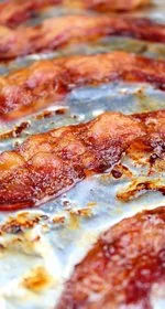 Oven baked bacon on an aluminum foil lined rimmed baking sheet. This is the vertical image.