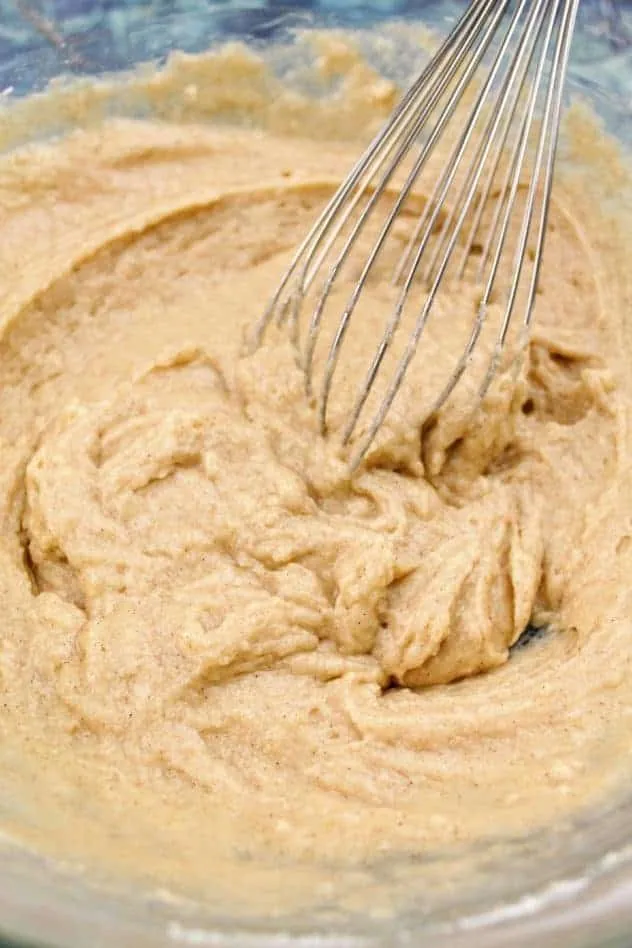 The batter in a large glass mixing bowl after mixing in all of the flour. A wire whisk sits in the bowl in the upper right.