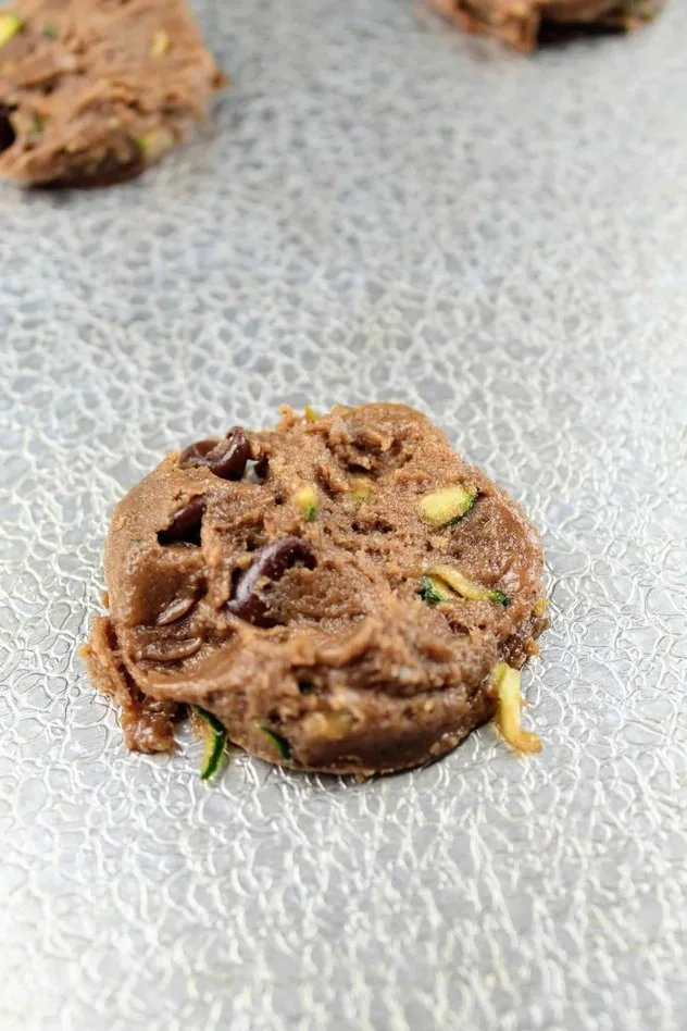 Vegan Chocolate Zucchini Cookies Process Step 4a A slightly flattened vegan chocolate zucchini cookie on a textured aluminum baking sheet before baking.
