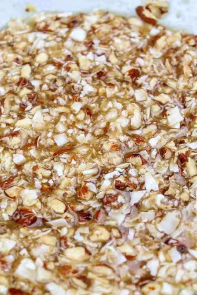 Vegan Almond Coconut Chocolate Chip Cookies Process Step 1 A mixture of extra light olive oil, granulated sugar, light brown sugar, unsweetened applesauce, vanilla extract, baking soda, Kosher salt, chopped coconut, and chopped almonds in a large glass bowl.