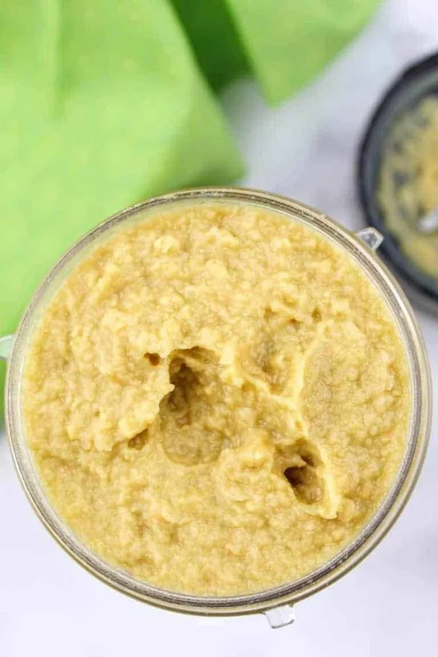 Vegan Key Lime Hummus Process Step 2 In the center is the final vegan key lime hummus all blended together in the blending container. In the upper left is a lime green tea towel and in the upper right is the bottom part of the blending container with the blades.